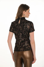 Load image into Gallery viewer, Model wearing a navy and gold floral lace short sleeve top and gold faux leather pants against a white background.