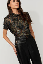 Load image into Gallery viewer, Model wearing a navy and gold floral lace short sleeve top and black faux leather pants against a white background.