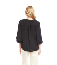 Load image into Gallery viewer, Woman wearing a black blouse and off-white pants against a white background.