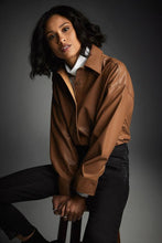 Load image into Gallery viewer, The Nell Nutmeg Leatherette Shirt by Joseph Ribkoff is the perfect way to update your wardrobe. Crafted with faux leather, it can be easily layered over different garments such as tanks, shirts, and lightweight knits, creating a fashionable and sophisticated look. Color- Nutmeg. Button down. Collared. Faux leather. No pockets.