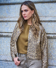 Load image into Gallery viewer, Woman wearing a leopard print jacket over a green top against a textured wall.