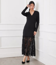 Load image into Gallery viewer, Woman wearing a black dress with a lace bottom and black heels leaning against a white wall.