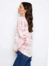 Load image into Gallery viewer, A woman wearing a long-sleeve knit sweater with a pink and white pattern, paired with blue jeans, against a plain white studio background.