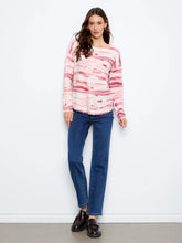 Load image into Gallery viewer, A woman wearing a long-sleeve knit sweater with a pink and white pattern, paired with blue jeans and brown loafers against a plain white studio background.