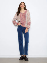 Load image into Gallery viewer, A woman stands against a white wall wearing a chunky knit sweater paired with dark blue jeans and black loafers.