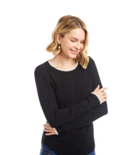 Load image into Gallery viewer, Woman wearing a black long-sleeve top with white trim and blue jeans against a white background.