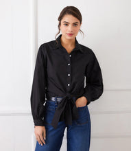 Load image into Gallery viewer, Woman wearing a long sleeve black shirt with a tie waist and blue jeans against a white background.