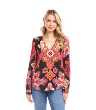 Load image into Gallery viewer, Woman wearing a colorful patterned blouse and blue jeans against a white background.