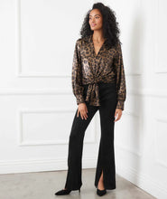 Load image into Gallery viewer, Woman wearing a leopard print blouse and black pants and heels against a white wall.