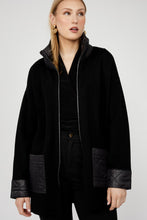 Load image into Gallery viewer, Woman wearing a long black jacket with rhinestone zipper and black pants against a white background.