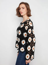 Load image into Gallery viewer, A woman wearing a black crochet top with a white daisy floral pattern, paired with blue jeans, photographed against a light gray studio background.