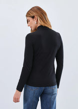 Load image into Gallery viewer, Woman wearing a black long-sleeve top and blue jeans against a light gray background.