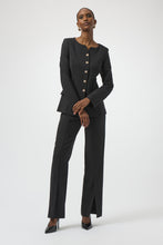 Load image into Gallery viewer, Woman wearing a black blazer with gold buttons, black lux pants with front slits and black patent heels against a white background.