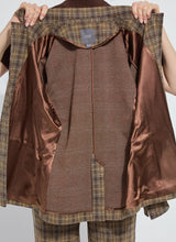 Load image into Gallery viewer, Model holding up a blazer to show the inner bronze lining against a white background.