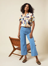 Load image into Gallery viewer, The Lyssé Margo Hi Waist Wide Crop Denim is a stylish and flattering wide-leg jean designed for comfort and elegance. Featuring a flowy palazzo shape, this denim pant offers an elongating look with a concealed patented waistband, belt loops, wide band inserts near the hem, side darts, and 70s-inspired patch pockets. The raw-edge hem allows for easy customization, making it simple to shorten if needed.