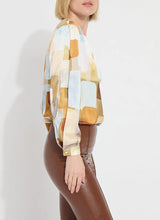 Load image into Gallery viewer, Crafted from two-way stretch Hammered Silk-Touch Satin, the Marie Blouse features an open neckline, asymmetrical front pleats, a high-low hemline, and double-box pleats on the sleeves for added volume. It fits true to size and pairs well with Ankle Elysse Vegan Leather pants in chalk and ankle boots. To remove any wrinkles after delivery, a gentle steaming or ironing is recommended.