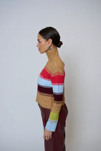 Load image into Gallery viewer, Woman wearing a colorful striped sweater and burgundy faux leather pants against a plain background.