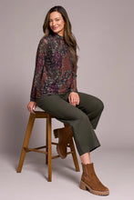 Load image into Gallery viewer, Woman wearing a patterned long-sleeve mesh top, green pants and brown boots against a plain background.