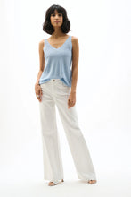 Load image into Gallery viewer, Woman wearing a light blue tank top, white pants and silver heels on a white background.