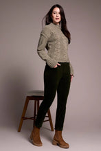 Load image into Gallery viewer, Woman wearing a green sweater and deep, dark green cord pants with brown boots standing next to a barstool against a plain background.