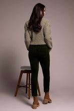 Load image into Gallery viewer, Woman wearing a green sweater and deep, dark green cord pants with brown boots standing next to a barstool against a plain background.