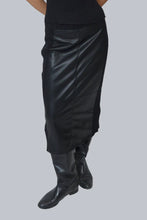 Load image into Gallery viewer, Model wearing long black leather skirt and black boots against a white background.