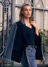 Load image into Gallery viewer, Woman wearing a black blazer with denim sleeves and blue jeans standing in front of decorative metal gates.