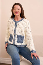 Load image into Gallery viewer, Woman wearing an eggshell cardigan with blue denim accents, blue jeans and beige heels sitting on a beige chair.