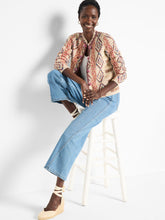 Load image into Gallery viewer, A perfect addition to any outfit ensemble. The Color Weave Knit Jacket stands out with its bold, retro-inspired pattern, crafted from a luxurious, ultra-soft yarn blend. Designed to effortlessly coordinate with the current season's trends, this jacket also boasts a sophisticated woven tape trim and playful pom-pom detailing along the edges, while functional hook-and-eye closures add practicality to its eye-catching design.