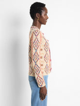 Load image into Gallery viewer, A perfect addition to any outfit ensemble. The Color Weave Knit Jacket stands out with its bold, retro-inspired pattern, crafted from a luxurious, ultra-soft yarn blend. Designed to effortlessly coordinate with the current season's trends, this jacket also boasts a sophisticated woven tape trim and playful pom-pom detailing along the edges, while functional hook-and-eye closures add practicality to its eye-catching design.