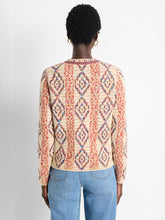 Load image into Gallery viewer, A perfect addition to any outfit ensemble. The Color Weave Knit Jacket stands out with its bold, retro-inspired pattern, crafted from a luxurious, ultra-soft yarn blend. Designed to effortlessly coordinate with the current season's trends, this jacket also boasts a sophisticated woven tape trim and playful pom-pom detailing along the edges, while functional hook-and-eye closures add practicality to its eye-catching design.