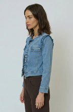 Load image into Gallery viewer, Woman wearing a denim jacket with ruffle trim and brown pants against a plain background.
