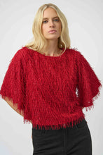 Load image into Gallery viewer, Woman wearing a red fringe sweater, black sparkle pants and black heels against a white background.