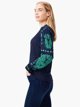 Load image into Gallery viewer, Woman wearing a navy-blue sweater with green floral patterns on long sleeves.