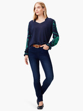 Load image into Gallery viewer, Woman wearing a navy-blue sweater with green floral patterns on long sleeves.