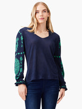 Load image into Gallery viewer, Woman wearing a navy-blue sweater with green floral patterns on long sleeves.