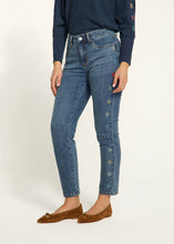 Load image into Gallery viewer, Expertly crafted with a nod to floral fashion, these Olivia Pencil Ankle Denim in Medium Wash, project understated chic. Delicate flower embellishments adorn the outer side of each leg, adding a distinct touch. The classic pencil cut flatters the figure and offers a sleek and modern silhouette.