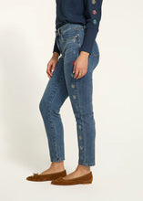 Load image into Gallery viewer, Expertly crafted with a nod to floral fashion, these Olivia Pencil Ankle Denim in Medium Wash, project understated chic. Delicate flower embellishments adorn the outer side of each leg, adding a distinct touch. The classic pencil cut flatters the figure and offers a sleek and modern silhouette.