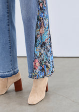 Load image into Gallery viewer, Close-up of a person wearing blue jeans with floral inserts and beige ankle boots against a neutral background.