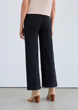 Load image into Gallery viewer, Woman wearing black wide-leg jeans and beige shoes against a plain background.