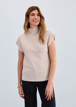 Load image into Gallery viewer, Woman wearing a beige sleeveless sweater and black pants against a plain background.