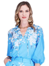 Load image into Gallery viewer, Woman wearing a blue floral blouse on a white background.
