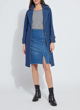 Load image into Gallery viewer, Woman wearing a blue denim trench coat, denim skirt, and black boots against a white background.