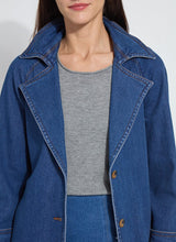 Load image into Gallery viewer, Close up of a woman wearing a blue denim trench coat, grey tee and denim skirt against a white background.