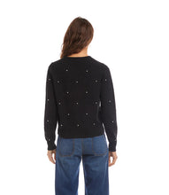 Load image into Gallery viewer, Woman wearing a black sweater with pearl embellishments and blue jeans against a white background.