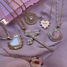 Load image into Gallery viewer, Collection of gold necklaces with various pendants on a pink fabric background.