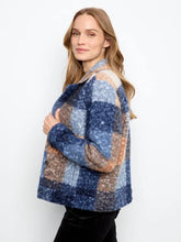 Load image into Gallery viewer, A woman standing sideways, modeling a boucle plaid short coat with blue, beige, and orange sections, and black pants against a plain white background.