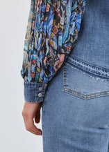 Load image into Gallery viewer, Close-up of a person wearing a floral shirt and blue jeans against a white background.