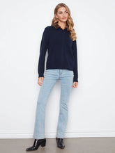 Load image into Gallery viewer, A woman modeling a navy blue long-sleeve cardigan with a collar, paired with light-wash blue jeans and black ankle boots, standing against a plain white wall.