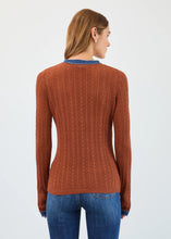 Load image into Gallery viewer, Woman wearing a bronze sweater with blue trim and blue jeans against a white background.